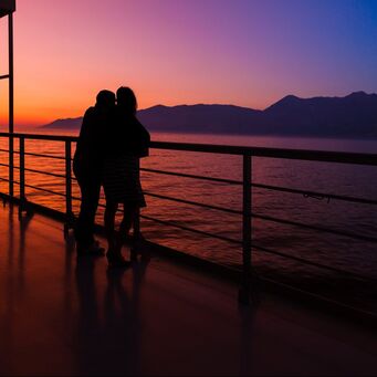 Couple on a balcony enjoying the sunset on a cruise.
